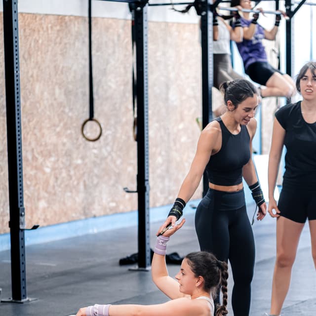Companeras ayudando a una atleta durante el ejercicio